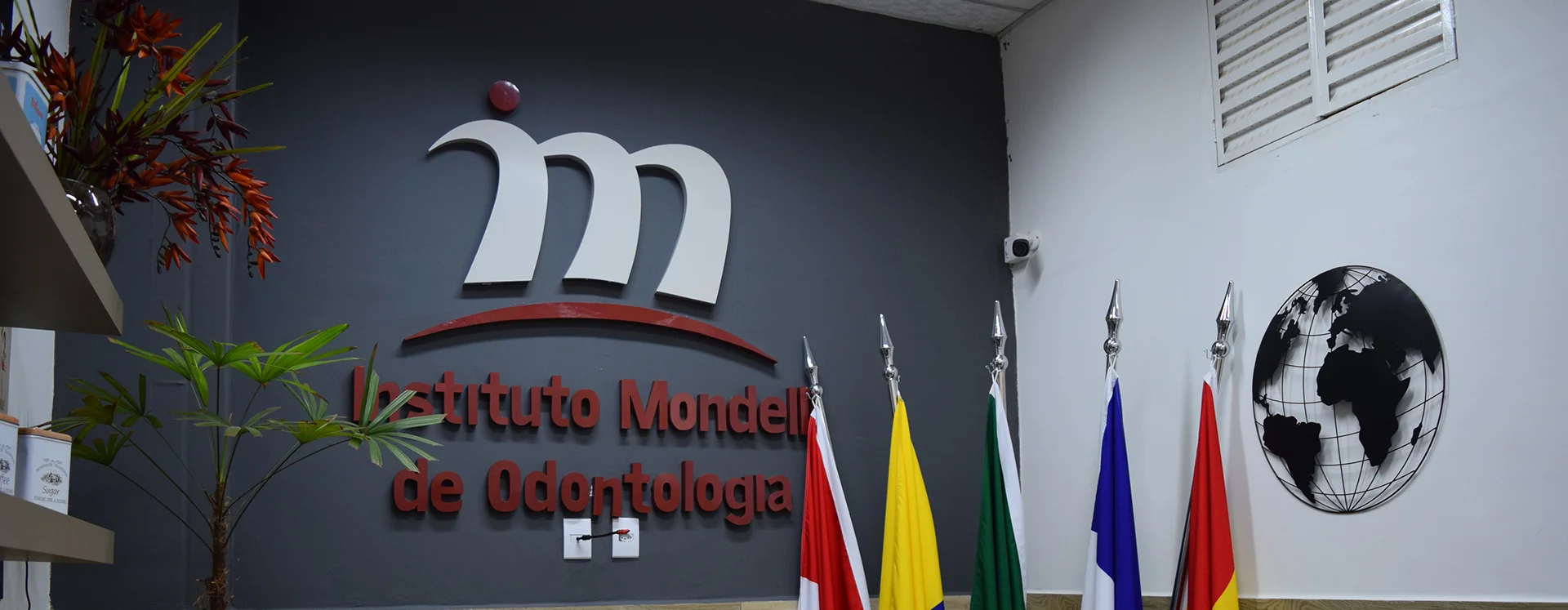 Recepção do Instituto Mondelli de Odontologia, com a marca do instituto e bandeiras